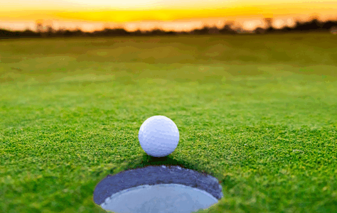 Golf ball sitting by the hole on a golf course