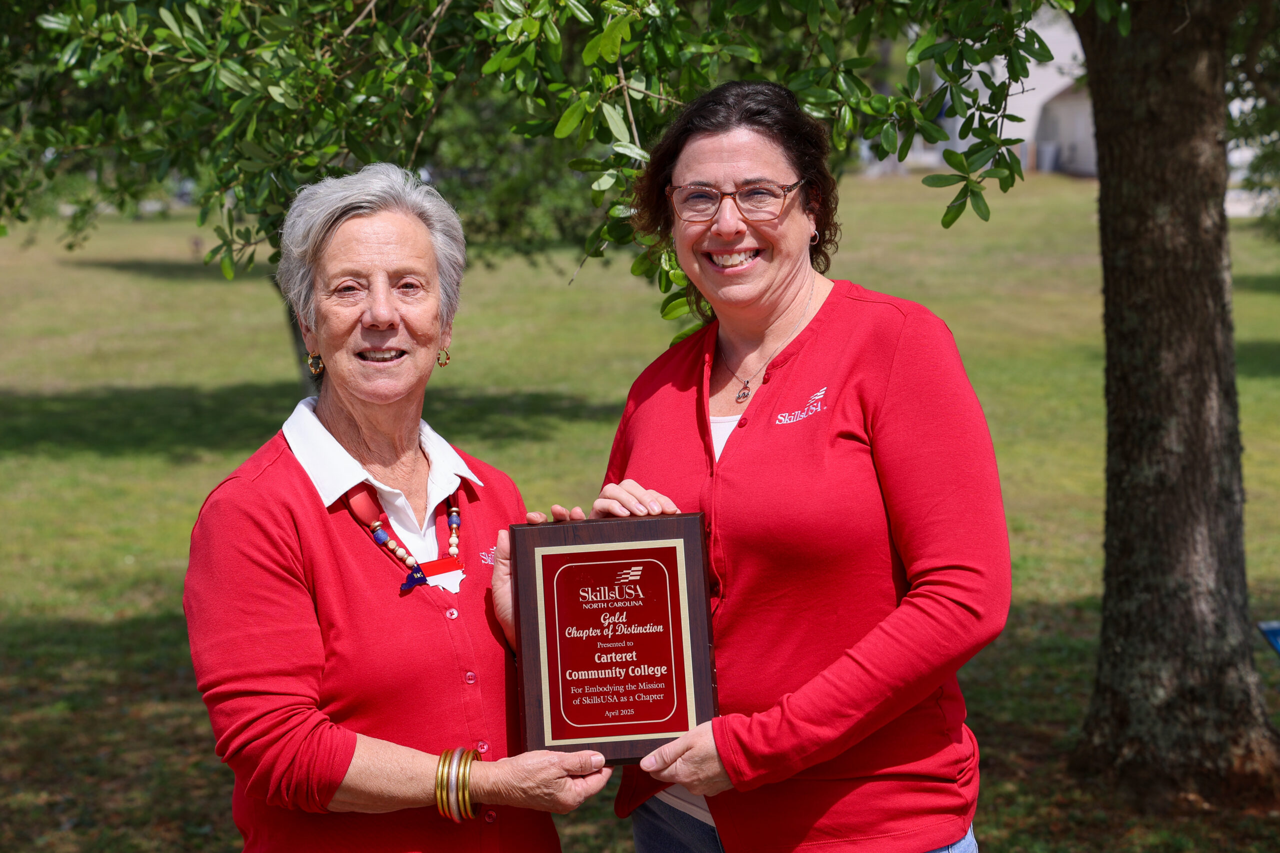 Two ladies standing side by side holding a plaque for SkillsUSA.