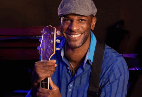 Picture of Alex Williams wearing a hat and holding a guitar
