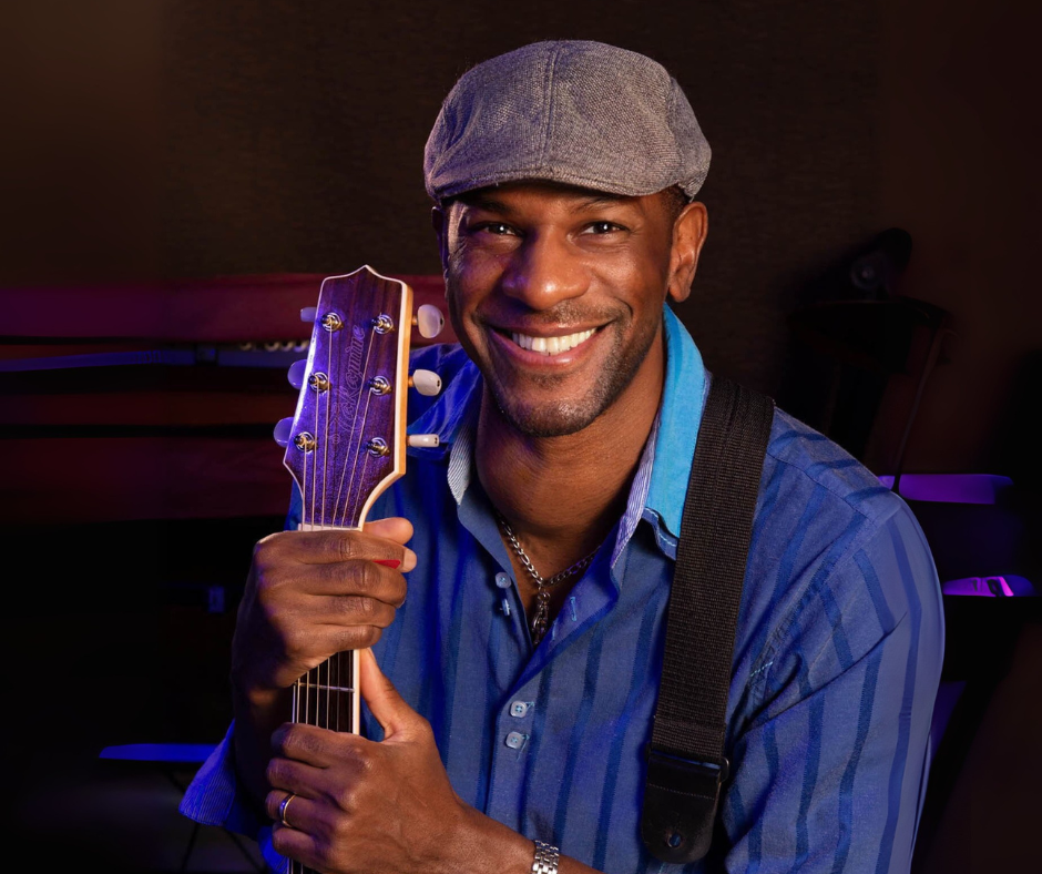 Picture of Alex Williams wearing a hat and holding a guitar