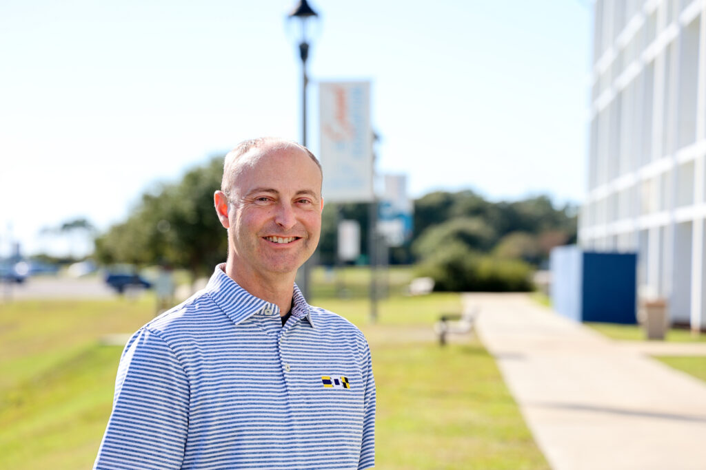 A male standing on campus next to a building