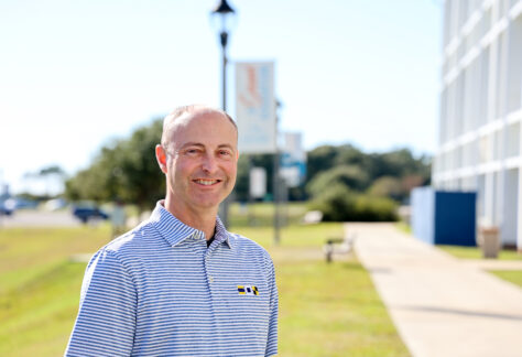 A male standing on campus next to a building