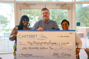 three people holding up a check for 1,000.00