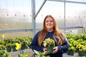 a female student in the greenhouse holding a plant