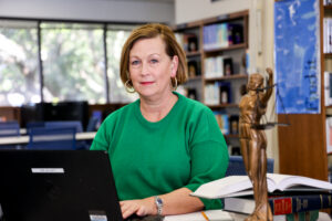 a female student sitting at the desk with books and a laptop in the library
