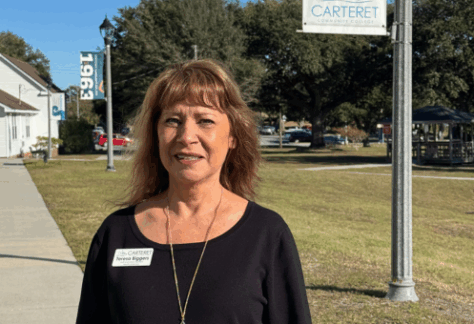 a lady standing outside on campus with a flagpole behind her.