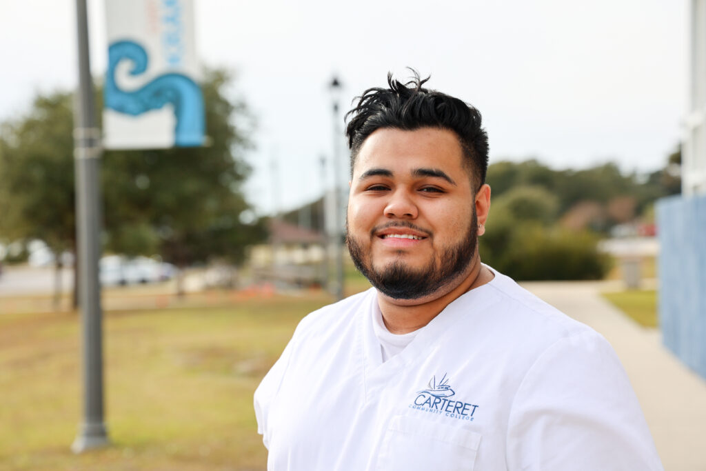 Male student in a white uniform outside.