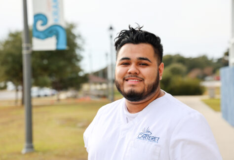 Male student in a white uniform outside.
