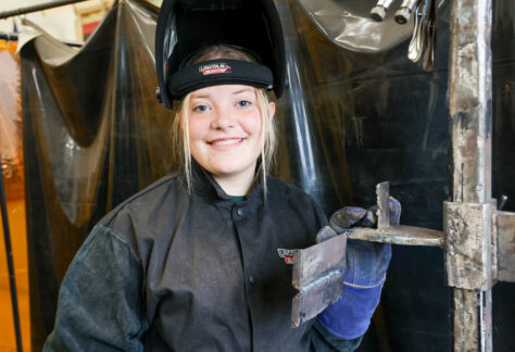a female student in welding gear in a welding shop