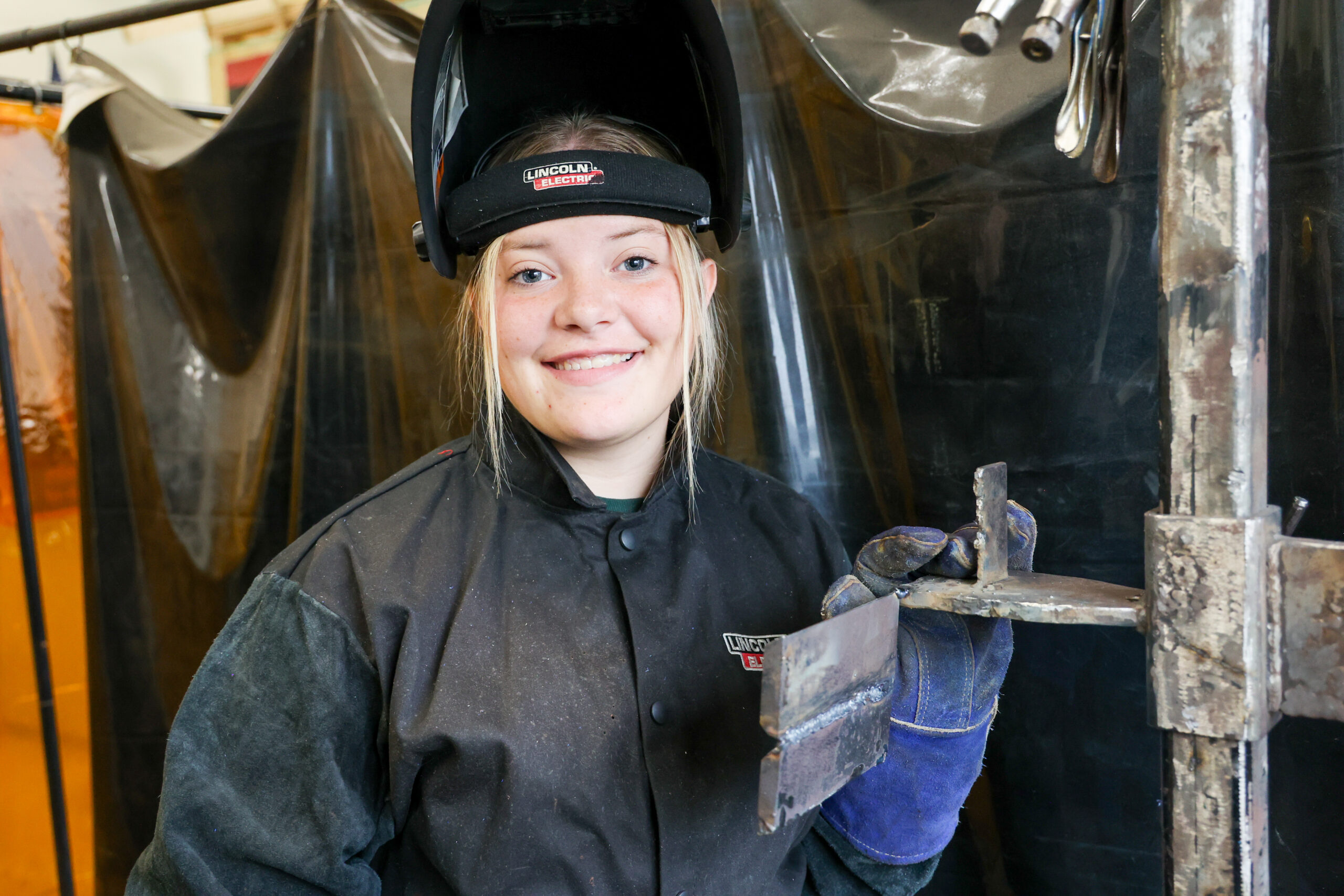 a female student in welding gear in a welding shop