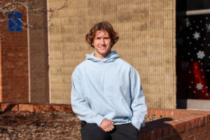 a make student sitting outside on a brick wall
