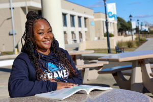 female student sitting at the picnic table reading a book