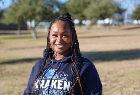 A female student standing outside with a blue kraken sweatshirt on