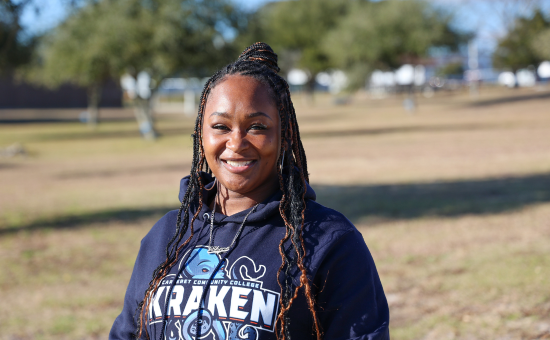 A female student standing outside with a blue kraken sweatshirt on