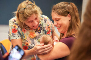 a picture of a woman hold a baby in her arms smiling