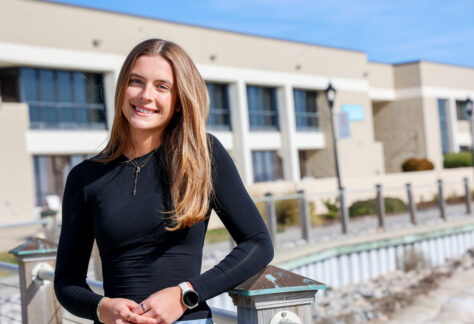 A female in a black shirt standing outside by the water front