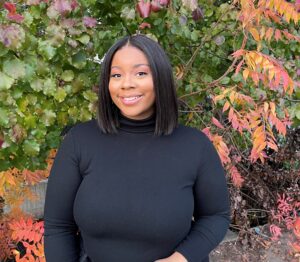 a black female outside in front of tress and flowers