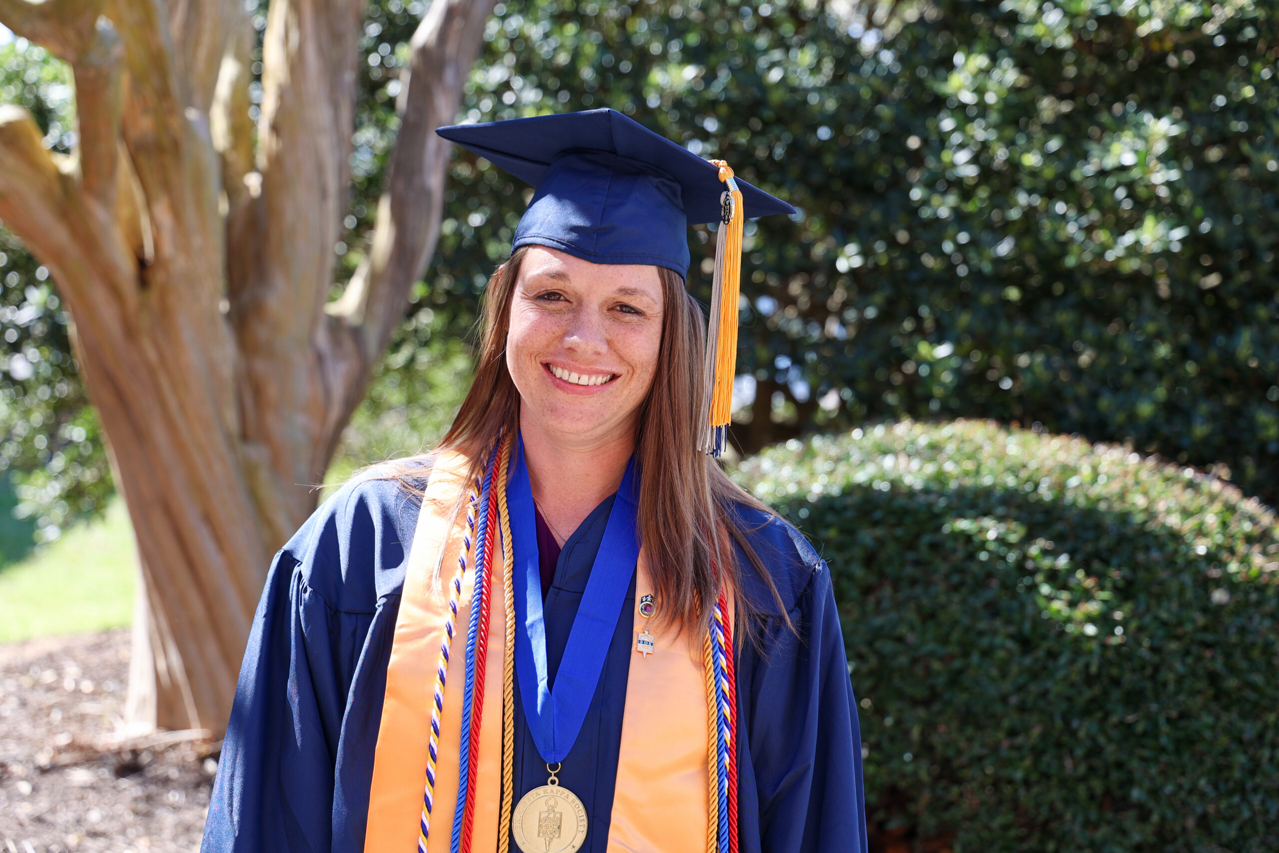 A female student in a graduation blue cap and gown outside