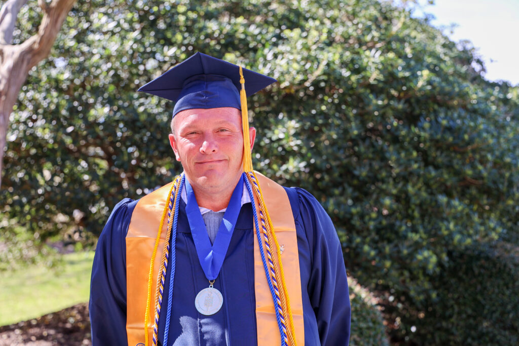 White male student in a cap and gown.