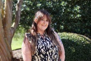 female standing outdoors with a tree in the background