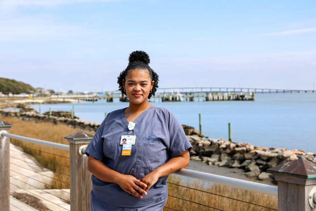 A female student in her scrubs outside by the waterfront