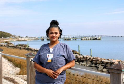 A female student in her scrubs outside by the waterfront