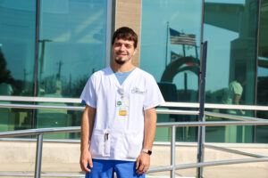 Male student standing outside in scrubs