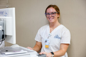 Female student with a hospital cart standing against the wall