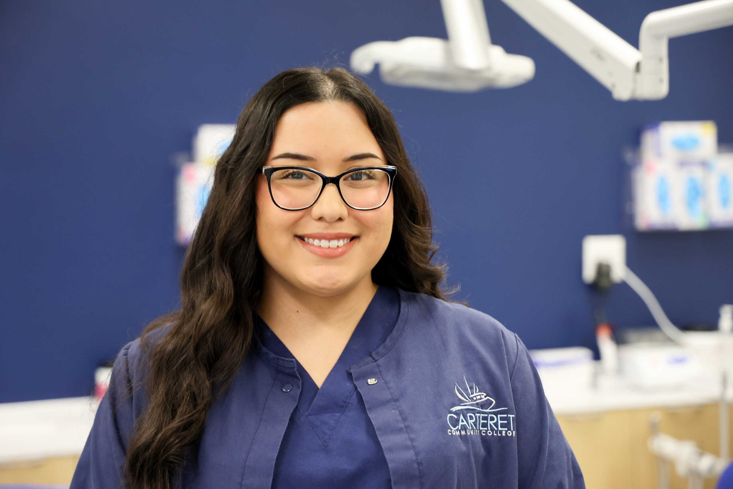 female student in a blue uniform smiling in a dentist office