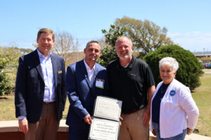 a student standing beside 3 people holding an award in his hands